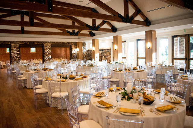 A wedding reception in a large room at Highlands Ranch Mansion with tables and chairs.