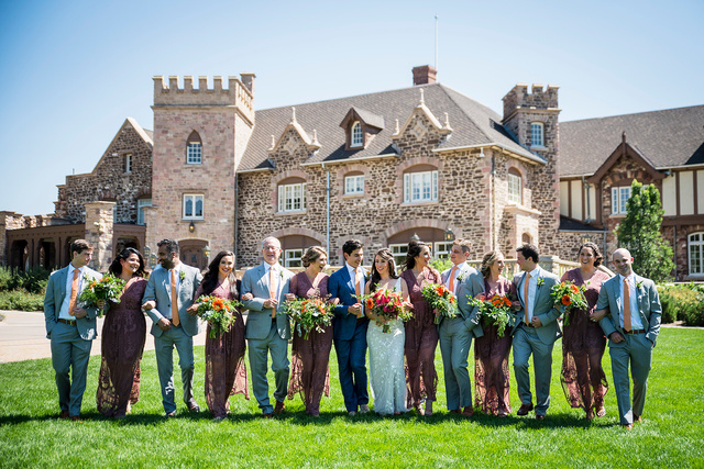 A group of bridesmaids and groomsmen standing in front of a castle.