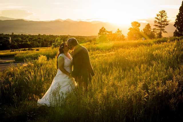 A bride and groom kiss in a field at sunset at Highlands Ranch Mansion.