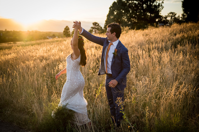 A bride and groom dancing in a field at golden hour at The Highlands Ranch Mansion in Colorado.