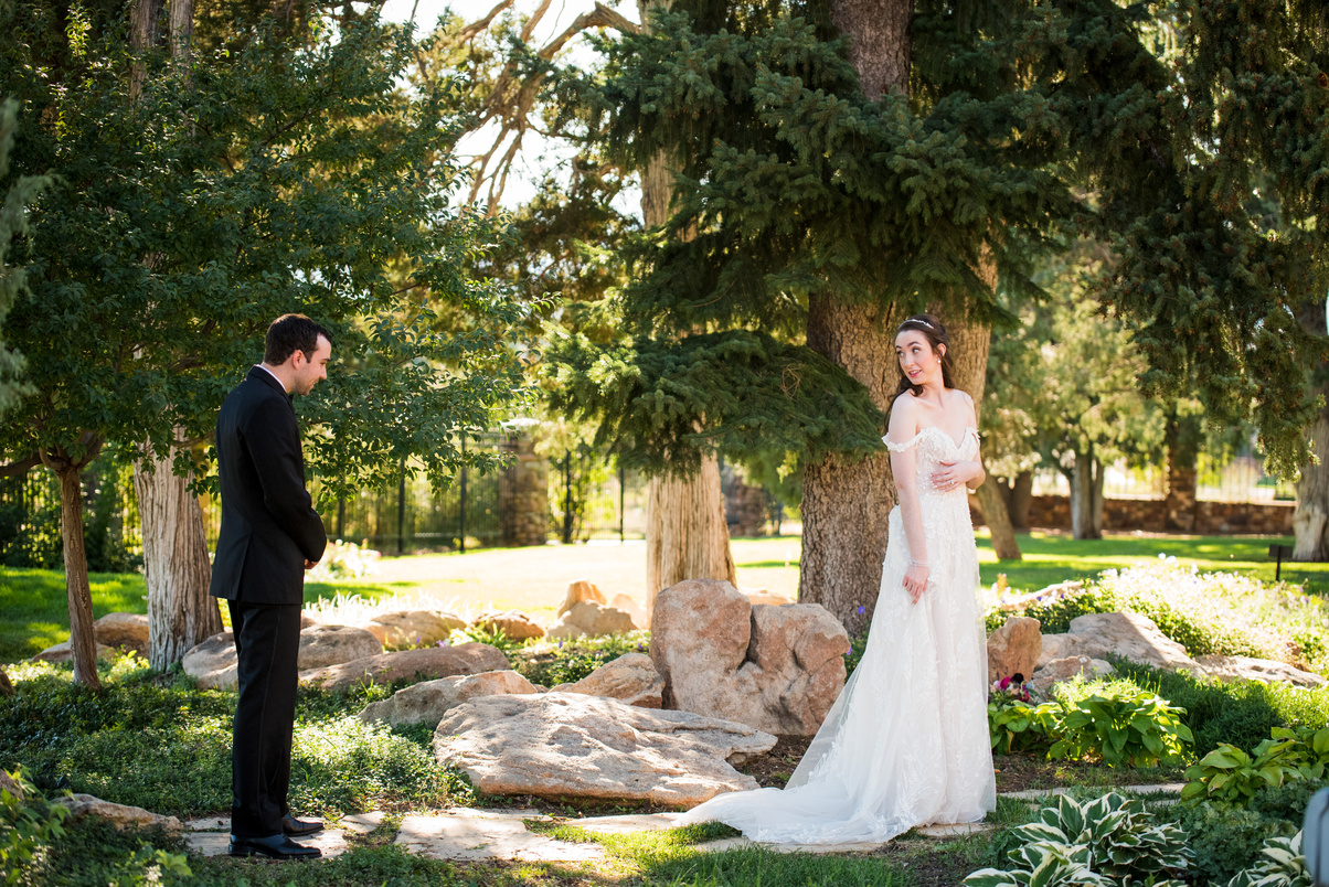 A groom looks at the bride's dress during their first look at The Highlands Ranch Mansion in Colorado.