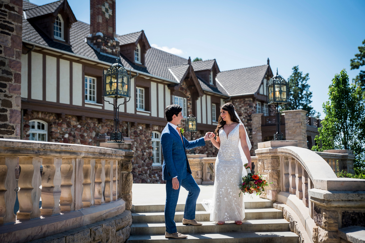 A bride and groom stand on the steps in front of The Highlands Ranch Mansion in Highlands Ranch, Colorado.