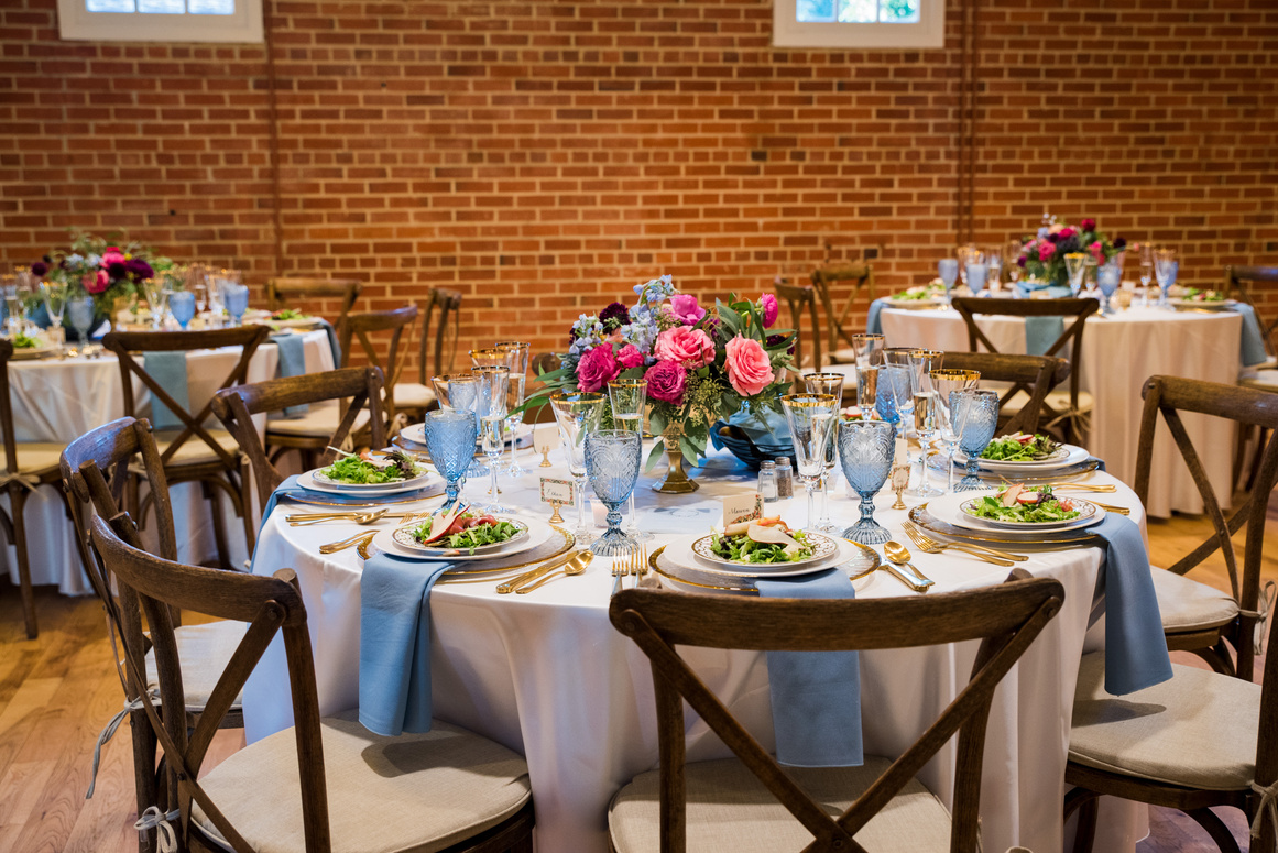 Tables set for a wedding reception in a brick walled room.