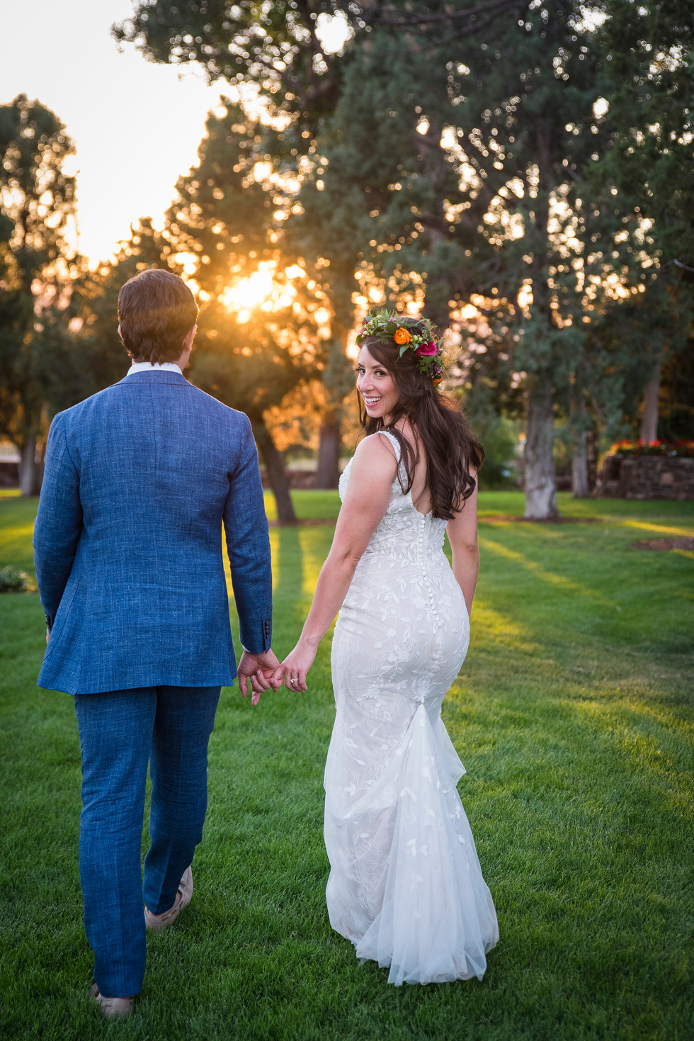A bride and groom walking hand in hand at sunset at Highlands Ranch Mansion, captured by Colorado wedding photographer, Two One Photography.