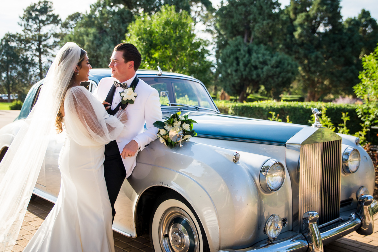 A bride and groom in front of Rolls Royce at Highlands Ranch Mansion.